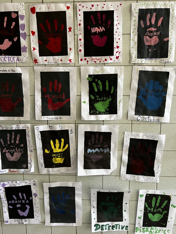 Huellas de manos pintadas por los estudiantes, cada una con el nombre y la profesión que sueñan