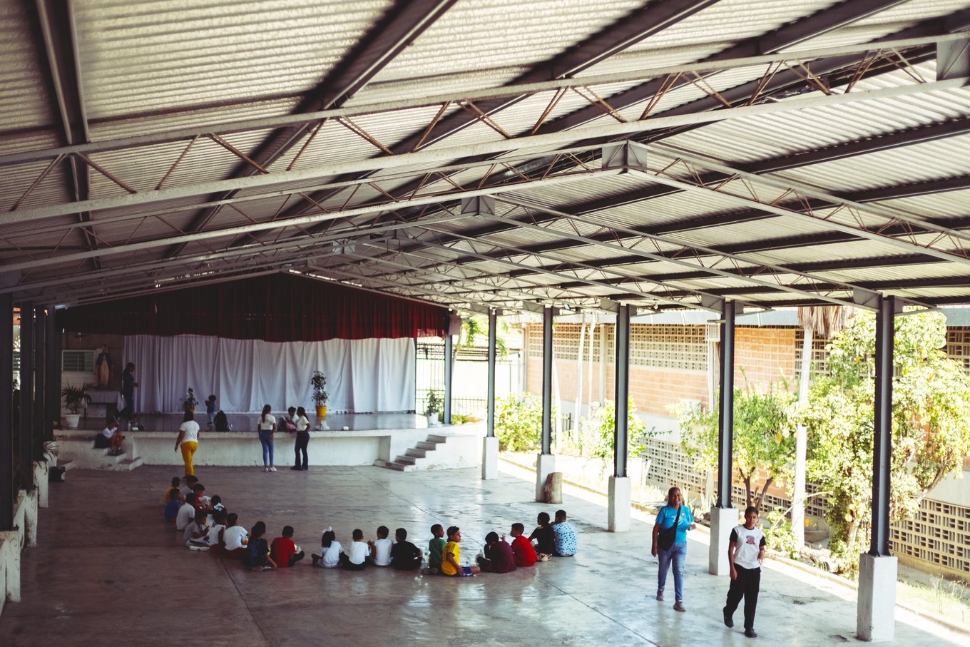 Niños sentados en ronda en el patio techado de un colegio